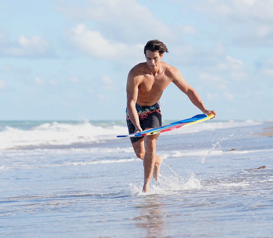 guy running preparing to start a skimboard ride at the beach