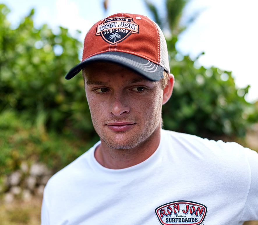 guy among beach dunes wearing rust colored hat