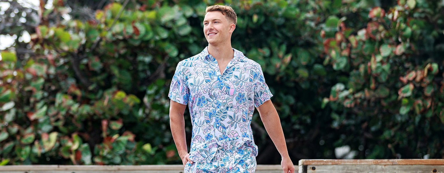 guy wearing the ron jon bird of paradise button-up shirt walking on the boardwalk