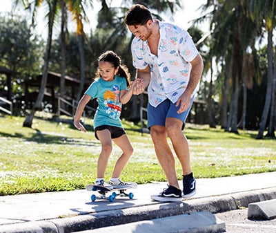 Dad helping their child skateboard