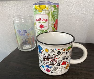 a glass, insulated tumbler, and coffee mug together on an end table