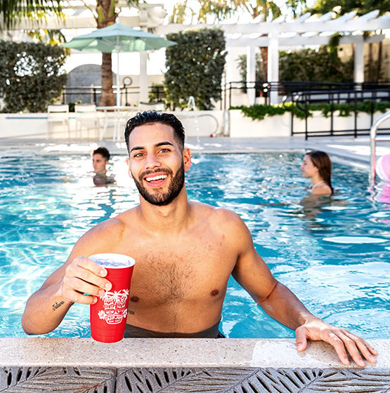 guy at the edge of the pool with a red ron jon drink cup