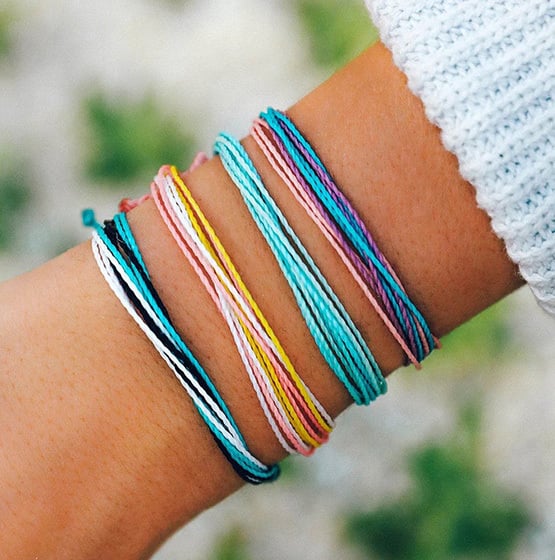 woman's wrist showing off multiple colorful Pura Vida bracelets