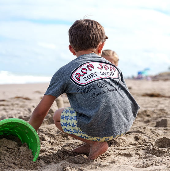 boy playing at the beach wearing ron jon surf shop shirt