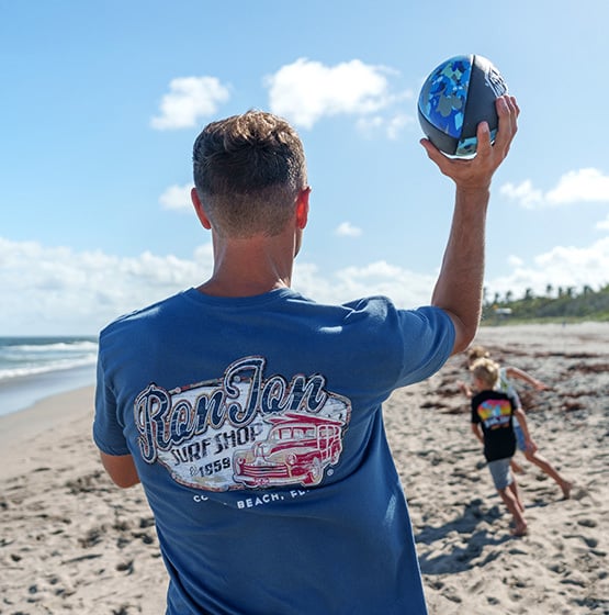 a dad throwing a football to his kids at the beach